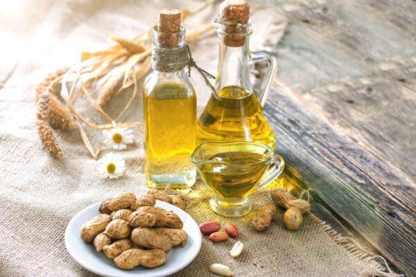 Peanut oil and peanuts on a wooden table on a sunny day