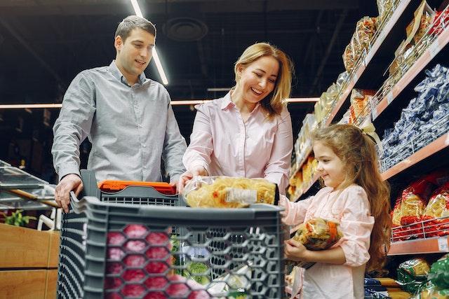 A family at a grocery store talking about products as one of the examples of how to educate your children about food secure future